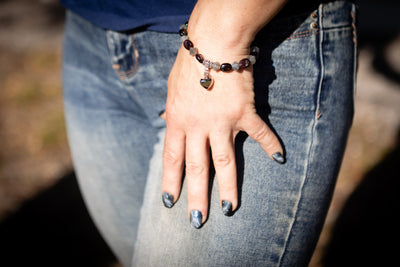 Hand with cremation bracelet and blue jeans against a blurred background